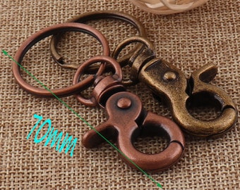 May include: Two antique-style keychains with a copper and brass finish. The keychain on the left has a large, round ring and a smaller, round ring. The keychain on the right has a hook-shaped clasp. The keychains are 70mm long.