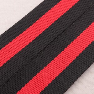 May include: Black and red striped fabric with a woven texture.