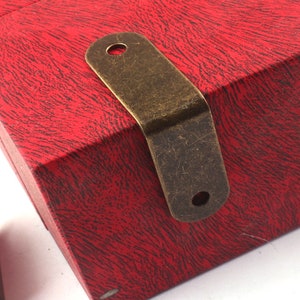 Puede incluir: Esquina de refuerzo de latón antiguo con dos agujeros. La esquina es una pieza de herraje decorativa para muebles o manualidades.