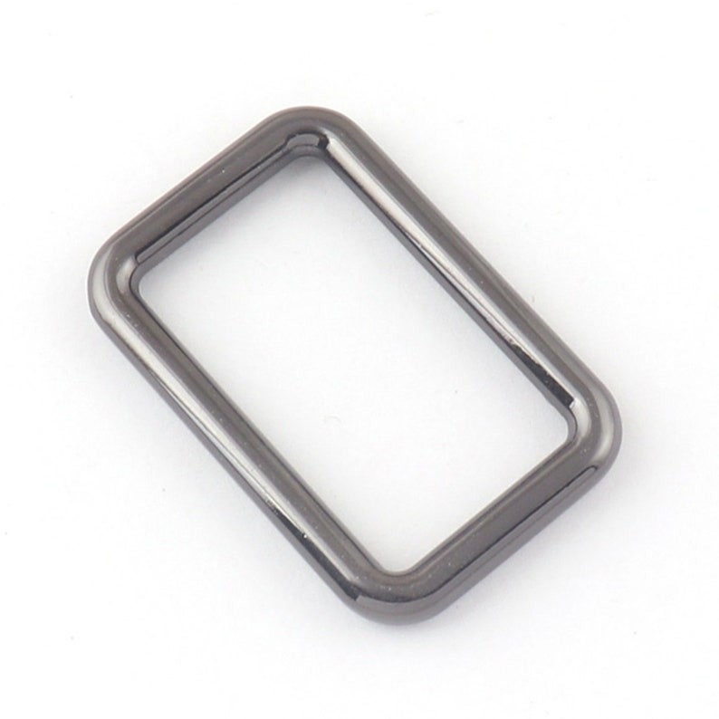 May include: A black metal D-ring with a rectangular shape.