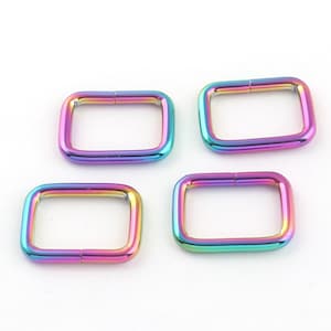 Könnte beinhalten: Vier regenbogenfarbene D-Ringe aus Metall. Die Ringe sind rechteckig und haben eine glatte, polierte Oberfläche.