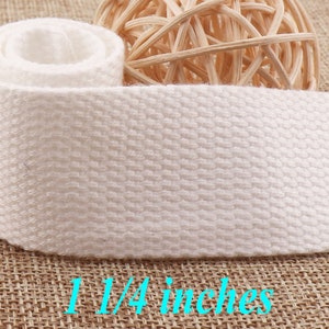 May include: White cotton webbing with a textured surface. The webbing is 1 1/4 inches wide.