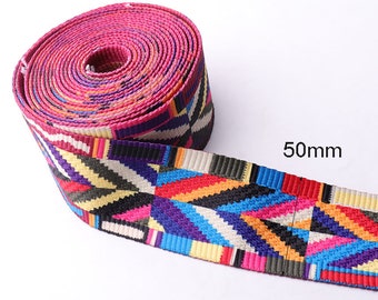 May include: A colorful woven webbing with a geometric pattern in shades of pink, yellow, blue, red, black, and white. The webbing is 50mm wide.