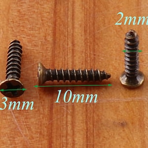 May include: Three antique gold-toned screws with a 10 mm length, 3 mm width, and 2 mm height.