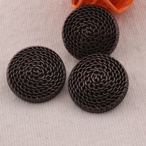 May include: Three round, bronze-colored buttons with a woven, spiral design.