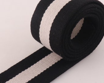 May include: Black and white striped cotton webbing. The webbing is rolled up and has a white stripe down the center.