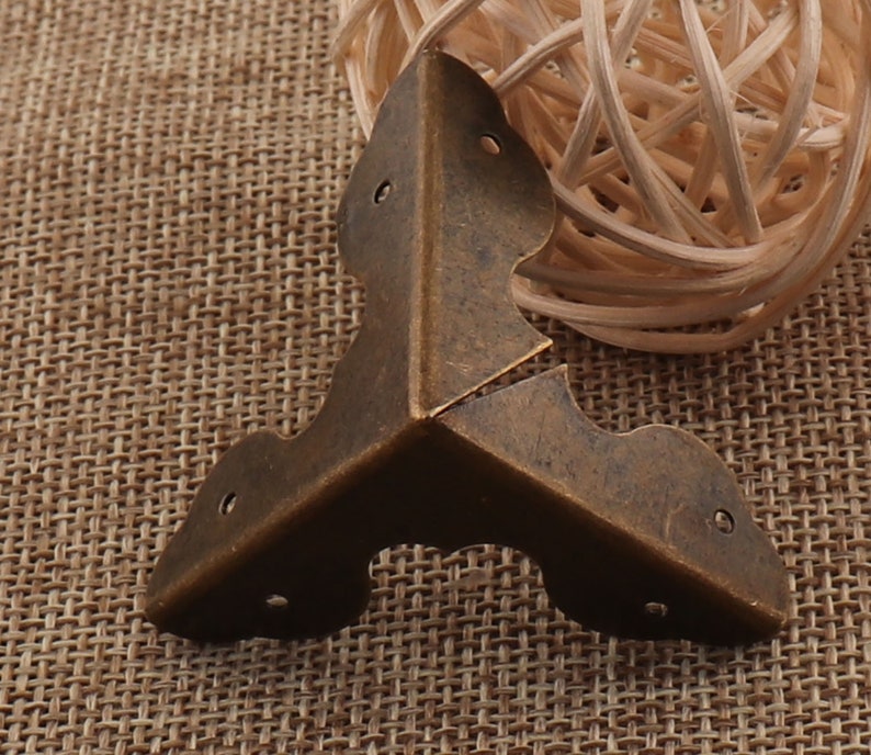 May include: Antique brass corner brace with a decorative design. The brace is made of metal and has a distressed finish.