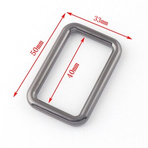 May include: A silver metal rectangular ring with rounded edges. The ring measures 33 mm wide, 40 mm tall, and 50 mm long.