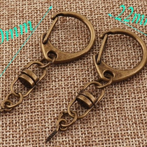May include: Two antique gold keychains with a swivel clasp and a 60mm chain with a screw-on end. The keychains are 22mm in diameter.