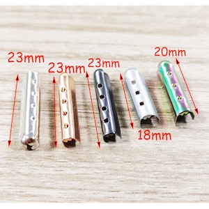 May include: Five metal cord ends in different colors and sizes. The cord ends are 23 mm long and 18 mm wide. The colors are silver, rose gold, black, silver, and iridescent green.