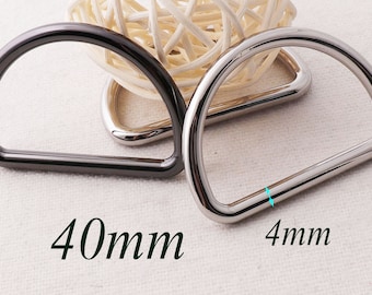Puede incluir: Dos anillos en D de metal, uno negro y otro plateado, con un diámetro de 40 mm y un grosor de 4 mm.