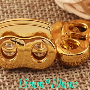 Puede incluir: Dos cierres de metal de color dorado con dos agujeros cada uno. Los cierres miden 15 mm por 19 mm.