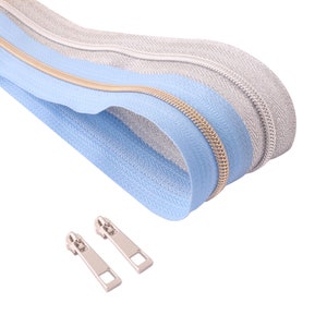 May include: A close-up of a light blue and silver zipper with a gold zipper pull. Two silver zipper pulls are also shown.