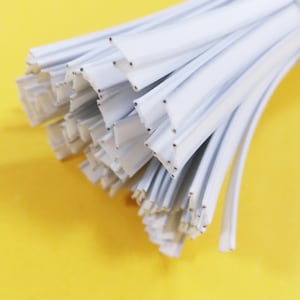 May include: A bundle of white plastic cable ties with small holes along the edges. The ties are bundled together and are ready to be used for organizing cables.