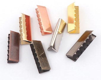 May include: Assortment of metal slider buckles in various finishes, including gold, silver, bronze, and copper. The buckles have a serrated edge and are designed for use with straps or webbing.
