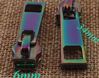 May include: Two iridescent zipper pulls, one measuring 3.4 inches long and the other measuring 0.6 inches wide. The zipper pulls are a rainbow of colors, including purple, blue, green, and red.
