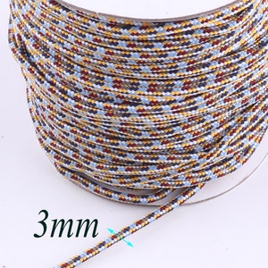 Op de afbeelding: Een spoel met 3 mm dik, veelkleurig koord. Het koord is een mix van blauw, rood, geel en wit.