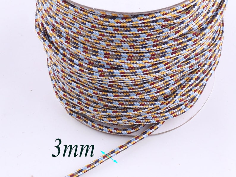 Op de afbeelding: Een spoel met 3 mm dik, veelkleurig koord. Het koord is een mix van blauw, rood, geel en wit.