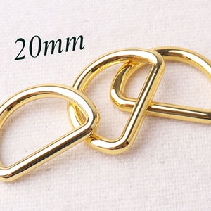 May include: Three gold-colored metal D-rings, each measuring 20mm in diameter. The rings are interlocked, showcasing their smooth, polished finish.