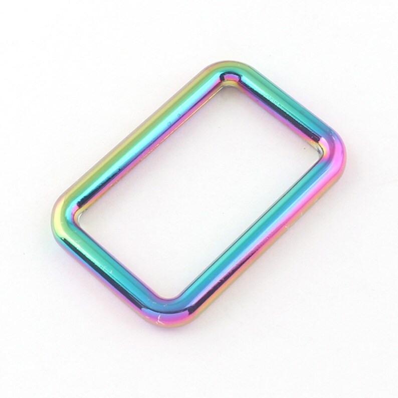 K&ouml;nnte beinhalten: Ein rechteckiger Ring aus regenbogenfarbenem, irisierendem Metall, auch D-Ring genannt, mit abgerundeten Kanten. Dieser Ring ist ein Hardware-Komponente f&uuml;r Bastelarbeiten, Taschen und andere Projekte.