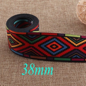 Peut inclure: Un rouleau de galon tissé coloré avec un motif géométrique dans des tons de rouge, bleu, vert, jaune et noir. Le galon mesure 38 mm de large.