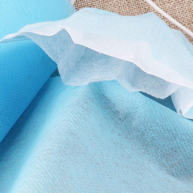 May include: Close-up of a light blue non-woven fabric, showing the texture and layers of the material.