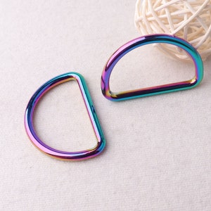 May include: Two iridescent rainbow-colored metal D-rings. The rings are smooth and shiny.