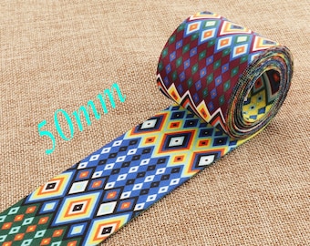May include: A 2-inch wide woven webbing with a colorful geometric pattern in shades of red, blue, yellow, green, and white. The pattern features diamonds, squares, and zigzags.