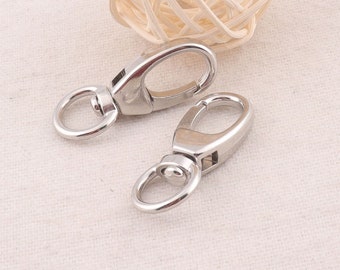 May include: Two silver metal swivel clasps with a round ring on one end. The clasps are commonly used for attaching items to bags, keychains, or other accessories.