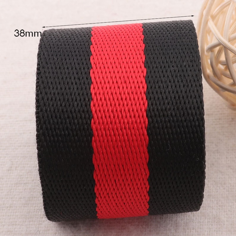 May include: Black and red woven webbing with a width of 38mm. The webbing has a black background with a red stripe running down the center.