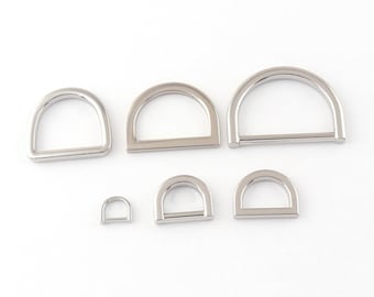 May include: A set of six silver-toned metal D-rings in various sizes. The rings are smooth and have a polished finish.