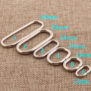 Puede incluir: Seis anillos metálicos ovalados de diferentes tamaños, de color plateado. Los anillos están dispuestos en orden de tamaño, con el anillo más grande en la parte superior y el anillo más pequeño en la parte inferior. Los anillos están etiquetados con los números del 1 al 6, y las medidas en milímetros se enumeran junto a cada anillo.