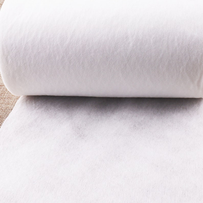 May include: A white roll of interfacing fabric, a type of fusible material used in sewing and quilting projects.