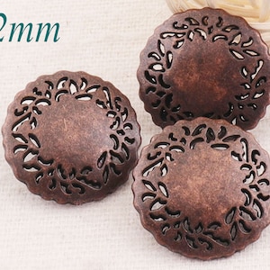 Puede incluir: Tres botones de metal de color cobre de 22 mm con un diseño floral decorativo. Los botones son circulares con un diseño recortado alrededor del borde.