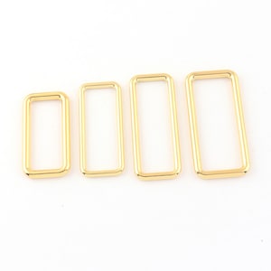 Puede incluir: Cuatro anillos rectangulares de metal de color dorado de diferentes tamaños.