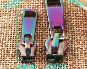 May include: Two iridescent zipper pulls, one measuring 3.8 inches long and 0.6 inches wide, and the other measuring 1.6 inches long and 0.4 inches wide.