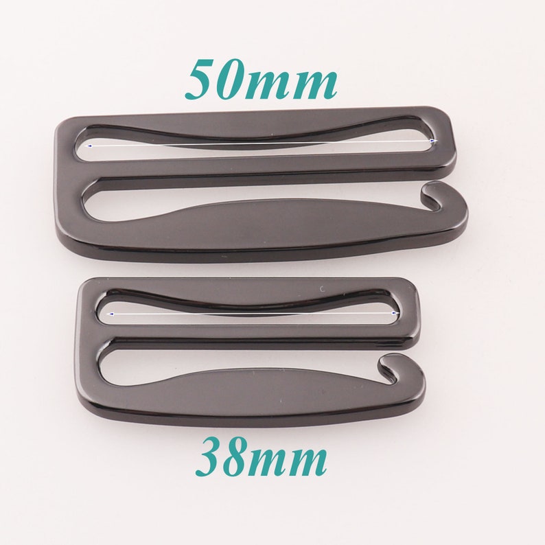 K&ouml;nnte beinhalten: Zwei schwarze Metall-BH-Verl&auml;ngerungen, eine mit einer L&auml;nge von 50 mm und die andere mit 38 mm.