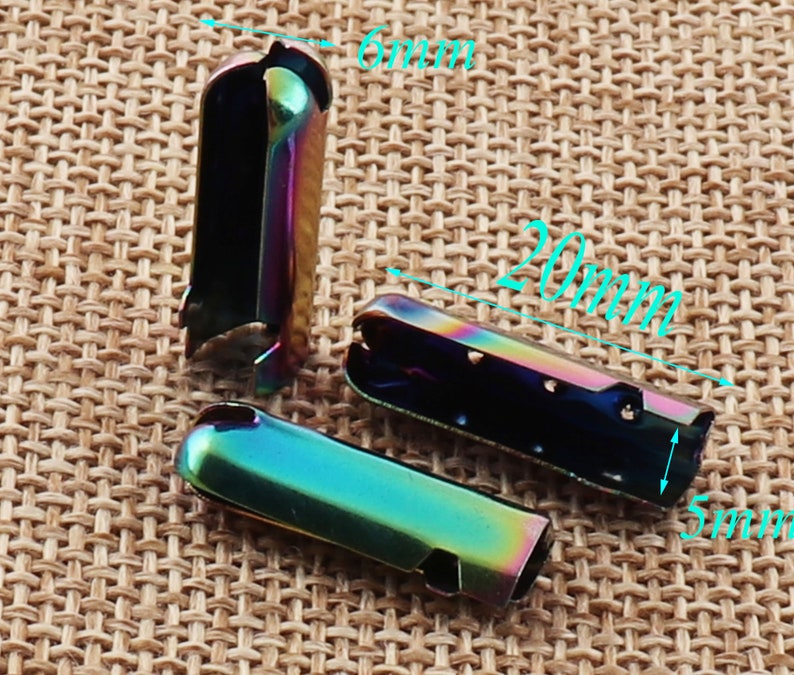 May include: Three iridescent metal cord ends, each approximately 0.8 inches long, 0.2 inches wide, and 0.2 inches high. The cord ends have a rainbow finish, with a mix of blue, green, and purple hues. They are designed to crimp onto the end of a cord.