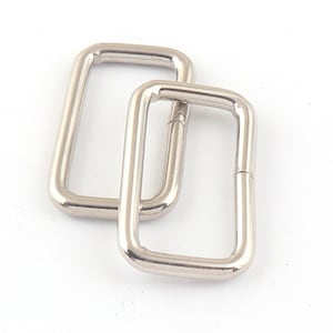 May include: Two silver metal rectangular D-rings. The rings are open on one side and closed on the other.