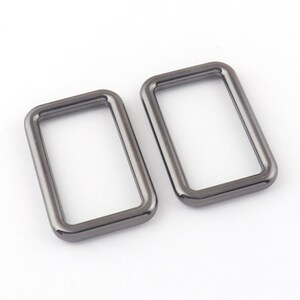 May include: Two silver-toned metal rectangular rings, each with a smooth, rounded edge.