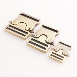 Può includere: Tre fibbie a sgancio laterale in metallo color oro antico di diverse dimensioni. Le fibbie hanno una finitura liscia e spazzolata e sono progettate per l'uso con cinghie o nastri.