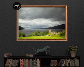 May include: A framed print of a Scottish landscape, showing a castle ruin by a loch under a dramatic, cloudy sky. The frame is a reddish-brown colour. The words "Digital Download" are in a black circle in the upper left corner.