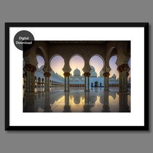 May include: A view through a series of arches of a white mosque with multiple domes. The arches are reflected in the wet floor of the courtyard.