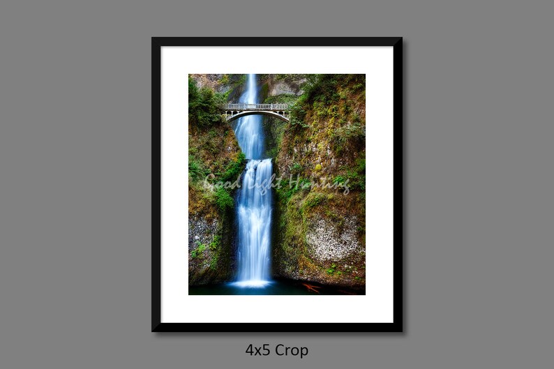 May include: A photograph of a waterfall cascading over a bridge in a lush green forest. The water is a vibrant blue and the bridge is made of wood.