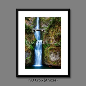 May include: A framed photograph of a waterfall cascading down a rocky cliff with a bridge over the top. The waterfall is surrounded by lush green foliage.