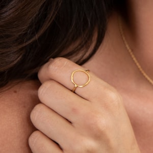 Peut inclure: Une bague en or avec un design simple en cercle ouvert. La bague est portée au doigt.