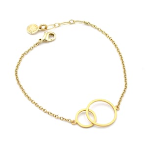 Puede incluir: Un brazalete de cadena dorada con dos círculos entrelazados. El brazalete tiene un cierre de langosta.