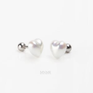 May include: A pair of heart-shaped pearl earrings with a silver post and backing. The earrings are white and have a glossy finish. The earrings are displayed on a white background.