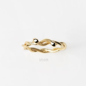 May include: A gold-toned ring with a twisted vine design. The ring features a textured surface and two small, rounded ends.