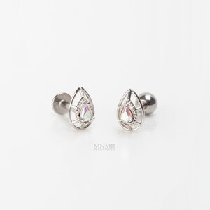 May include: A pair of silver teardrop-shaped earrings with a clear iridescent stone in the center of each teardrop. The earrings are designed to be worn as cartilage earrings.